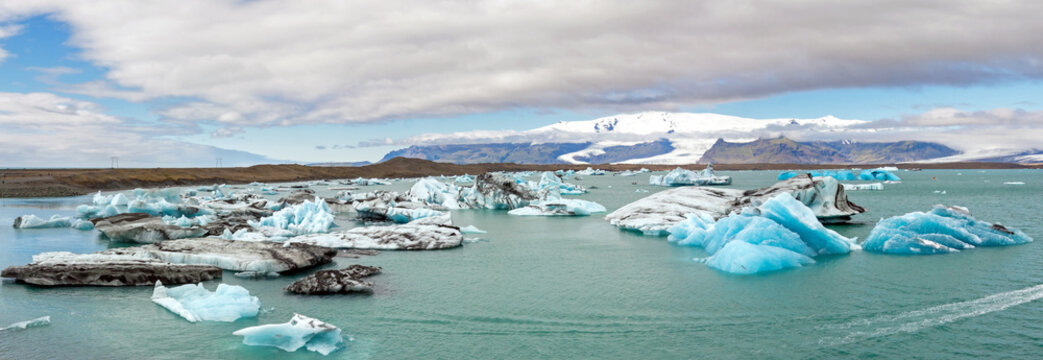 Icebergs in Jokulsarlon lagoon, Iceland, part of the Vatnajokull glacier national park. In the background the sunlit Hvannaldshnúkur, Iceland's highest peak.