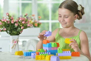 Obraz na płótnie Canvas Portrait of girl playing with colorful plastic blocks