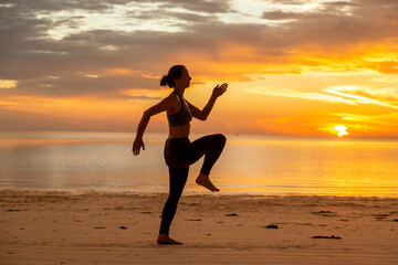 Fototapeta na wymiar Woman doing high knee skipping exercise on the beach