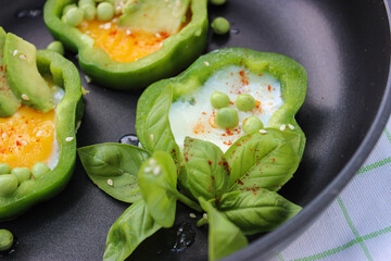 Healthy Breakfast of fried eggs in pepper rings with avocado and green peas