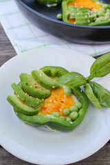 Healthy Breakfast of fried eggs in pepper rings with avocado and green peas