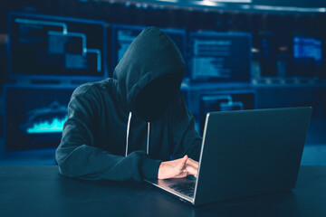 Hooded unknown hacker using laptop computer