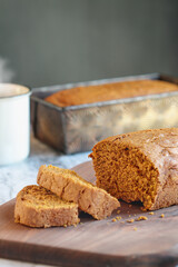 Fresh baked homemade pumpkin bread cut into slices on a cutting board with old knife. Selective focus with blurred foreground and background.