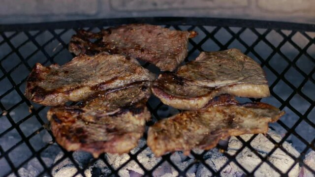 Beef rump steaks on the grill, being seasoned