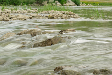 The flow of the river in the summer forest. Stones washed by water. Reflection on the water. water movement for a long exposure.