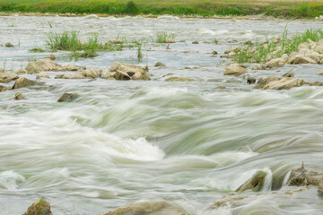 The flow of the river in the summer forest. Stones washed by water. Reflection on the water. water movement for a long exposure.