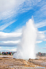 GEYSIR, ICELAND: Eruption of Strokkur geyser, observed by many tourists, on a day with remarkable cloudscape. 
