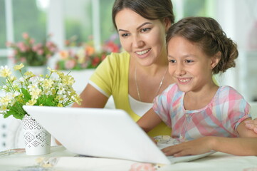 Portrait of mother and daughter using laptop