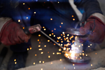 Obraz premium No focus.Close-up welder working with electrode at semi-automatic arc welding in manufacture production plant.Bright sparks from welding.