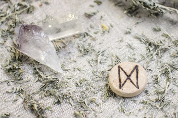 Scandinavian wooden rune Dagaz, Daeg on a rough linen cloth with amethyst crystalline, rock crystal and dried wormwood