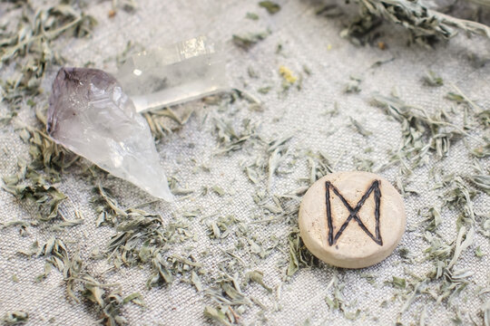 Scandinavian wooden rune Dagaz, Daeg on a rough linen cloth with amethyst crystalline, rock crystal and dried wormwood