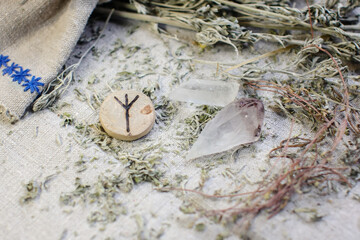 Scandinavian wooden rune Algiz, Elhaz on a rough linen cloth with amethyst crystalline, rock crystal and dried wormwood