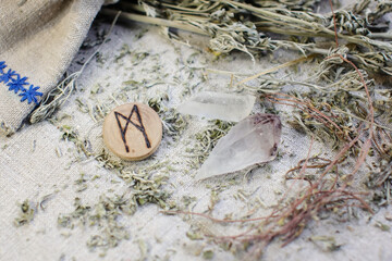 Scandinavian wooden rune Mannaz, Mann on a rough linen cloth with amethyst crystalline, rock...