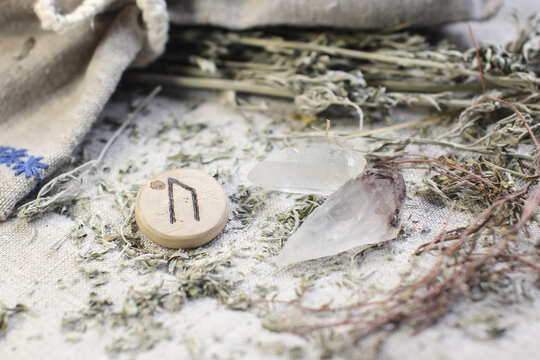 Scandinavian wooden rune Uruz, Ur on a rough linen cloth with amethyst crystalline, rock crystal and dried wormwood