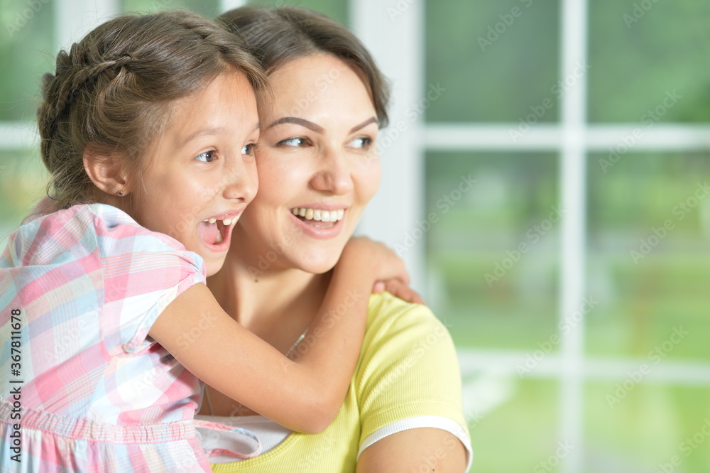 Poster Portrait of a charming little girl hugging with mom at home