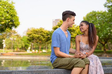 Naklejka premium Portrait of young multi ethnic couple relaxing together at the park