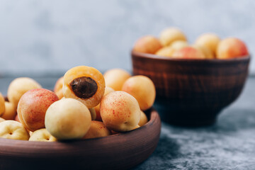 Lots of ripe yellow apricots close up in a crockery on the table