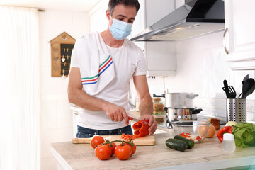 Man confined at home preparing vegetables in kitchen with mask