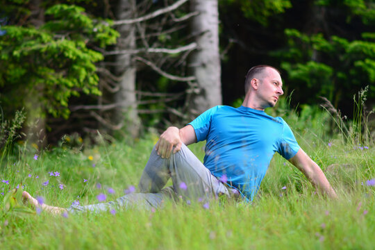 Fitness, Sport, Training And Lifestyle Concept - Man Stretching Lower Back For Spine Health On Outdoor Fitness Class In Park. Seated Spinal Twist.