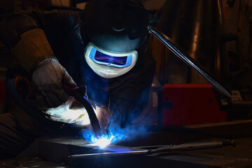 worker with protective mask welding metal and sparks