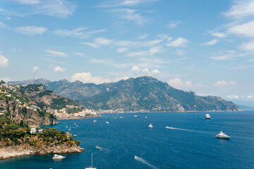 View from Conca dei Marini on Amalfi bay, Luxury boats traffic, ocean liner, fishing boats, tourist season. watercraft. Mountains and houses, buildings. Summer day. Amalfitana Italy