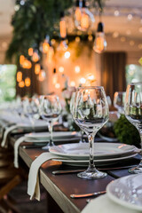 Wedding reception table with Edison bulbs and decor of greenery. Decoe. Wedding table setting