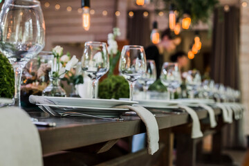 Wedding reception table with Edison bulbs and decor of greenery. Decoe. Wedding table setting