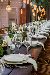 Wedding reception table with Edison bulbs and decor of greenery. Decoe. Wedding table setting