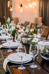 Wedding reception table with Edison bulbs and decor of greenery. Decoe. Wedding table setting