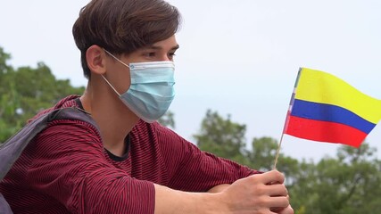 Travel during the coronavirus pandemic in the Colombia. Holidays, Traveling and COVID-19 measures. Social Distancing Summer Vacations. A young man in a protective medical mask with the flag - Powered by Adobe