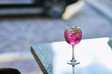 glass on the table. cocktail of pink with ice and orange
