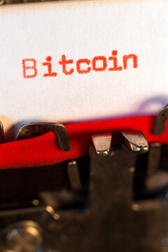 Bitcoin typed on typewriter on red. Bitcoin is a cryptocurrency invented in 2008 by an unknown person or group of people