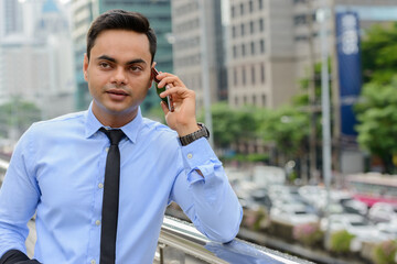 Young handsome Indian businessman in the city