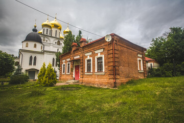 brick one-story house on a green lawn. Assumption Cathedral of the early 16th century in the city of Dmitrov, Russia. Orthodox church in the Dmitrov Kremlin.