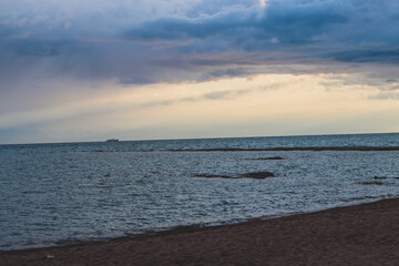 sunrise on the beach. beautiful summer scenery. rocks on the sand. calm waves on the water. clouds on the sky. wide panoramic view