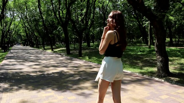 Cute redheaded teen girl strolls through a summer public Park