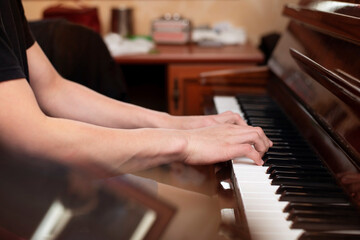 Obraz premium Hands of a young boy on the piano keys, a teenager plays a melody from a famous movie, he is engaged in music for self-development