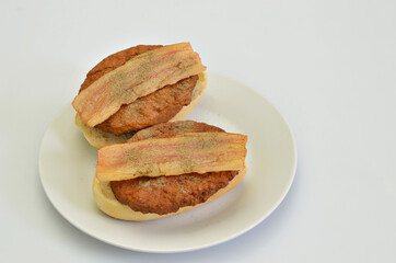 Two Sandwiches with Beef and Bacon on white Plate