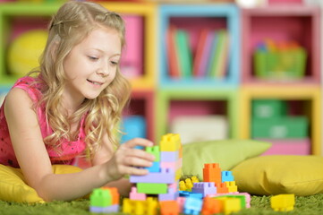 Little girl playing with colorful plastic blocks