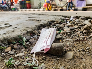 COVID-19 Waste or Litter Concept. Discarded Pink Medical Face Mask Thrown Away After Use on the street footpath.