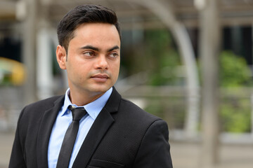 Fototapeta premium Young handsome Indian businessman in the city