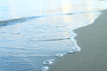 blurred wave of the sea on the evening sand beach