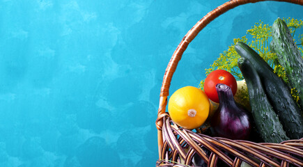 Fresh vegetables in the wicker basket against the blue wall. Copy space