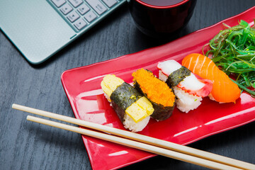 Tasty sushi sashimi set served with laptop on table