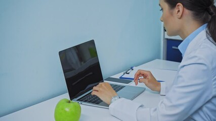Dentist using laptop and talking on smartphone in clinic - Powered by Adobe