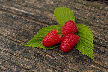 Ripe aromatic raspberries on a wooden background.