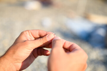 men's hands tying a fishing line on a fishing hook. selective focus. step 2