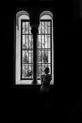 Young woman looking trough the window of an arabic palace