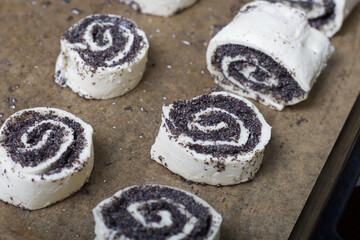 On a baking sheet are curls stuffed with poppy and walnuts. For baking.