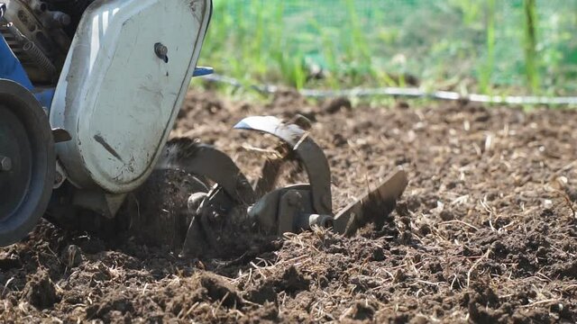 Garden tillers cultivator plowing the land. Close up. Selective focus. Slow motion